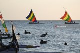 Pengunjung bermain perahu layar di Pantai Pasir Putih Situbondo, Jawa Timur, Minggu (17/6). Masyarakat memanfaatkan libur Lebaran dengan menikmati matahari terbenam, berenang di laut, naik perahu layar dan bermain kano. Antara Jatim/Seno/zk/18.