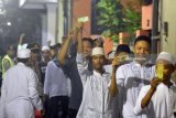 Sejumlah warga menunjukkan kupon ketika antre untuk mendapatkan zakat mal di kawasan Kalimas Madya Surabaya, Jawa Timur, Senin (11/6). Pembagian zakat mal yang dibagikan oleh seorang pengusaha biro perjalanan kepada 2.000 orang dengan nominal sekitar Rp100.000 hingga Rp200.000. Antara jatim/M Risyal Hidayat/zk/18