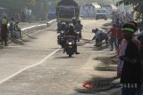 Warga menunggu pengendara motor memberi sedekah dengan melempar uang di Jembatan Sewo, Jalur Pantura Sukra Indramayu, Jawa Barat, Sabtu (9/6). Aksi mengambil uang sedekah menggunakan sapu tersebut dapat membahayakan keselamatan pengguna jalan terutama saat arus mudik. ANTARA JABAR/Dedhez Anggara/agr/18.