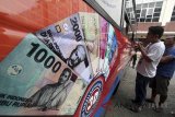 Warga menukarkan uangnya di mobil kas keliling Bank Indonesia di lahan parkir Cibinong City Center, Kabupaten Bogor, Jawa Barat, Selasa (5/6). Layanan penukaran uang Bank Indonesia pecahan kecil tersebut sangat membantu masyarakat khususnya warga yang membutuhkan penukaran uang menjelang lebaran. ANTARA FOTO/Yulius Satria Wijaya/18.
