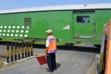 Petugas penjaga jalan lintasan ektra menghentikan kendaraan ketika sebuah kereta api melintas di perlintasan kereta api tanpa palang pintu di Desa Bedadung, Pakusari, Jember, Jawa Timur, Selasa (5/6). PT Kereta Api Indonesia (KAI) Daerah Operasi 9 Jember menambah sebanyak 94 petugas penjaga jalan lintasan (PJL) ekstra dan 47 pos untuk menjaga perlintasan sebidang rawan selama masa angkutan Lebaran 2018.Antara Jatim/Seno/zk/18.