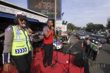 Petugas Sat Lantas Polres Bogor menghibur pengguna jalan dengan membuat konser mini pada saat pemberlakuan jalur satu arah jalur Puncak, Gadog, Kabupaten Bogor, Jawa Barat, Minggu (24/6). Hiburan yang dilakukan oleh Sat Lantas Polres Bogor tersebut bertujuan untuk menghibur pengendara yang terkena macet di jalur Puncak. ANTARA JABAR/Yulius Satria Wijaya/agr/18.