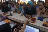 Petugas melayani penarikan dana kiriman dari luar negeri (remiten) di kantor PT Pos Indonesia Cabang Tulungagung, Tulungagung, Jawa Timur, Rabu (12/6). Sejak dua pekan menjelang Lebaran, transaksi remiten di daerah ini meningkat 25 persen, dari biasanya 250-300-an transaksi kini menjadi 300-400 transaksi per hari dengan besaran nominal penarikan rata-rata Rp1 juta - Rp2 juta per orang, 0ANTARA FOTO/Destyan Sujarwoko/zk/18