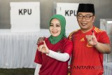 Calon Gubernur Jawa Barat nomor urut satu Ridwan Kamil (kanan) bersama istri Atalia Praratya (kiri) menunjukan tinta pada jarinya seusai menggunakan hak pilihnya di TPS 21 Bandung, Jawa Barat, Rabu (27/6). Pilgub Jabar diikuti empat pasang cagub dan cawagub dengan jumlah daftar pemilih tetap (DPT) sebanyak 31.735.133 pemilih. ANTARA JABAR/M Agung Rajasa/agr/18.
