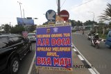 Sejumlah pengendara melintas di samping spanduk jalur Puncak, Gadog, Bogor, Jawa Barat, Rabu (13/6). Satuan Lalu Lintas Polres Bogor, Jawa Barat memasang sejumlah spanduk, dan baliho (banner) dengan kata-kata unik untuk menarik perhatian pengendara yang melintas di kawasan Puncak untuk meminimalisir angka korban kecelakaan saat arus mudik dan balik Lebaran 2018. ANTARA JABAR/Yulius Satria Wijaya/agr/18.
