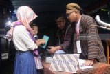 Petugas Kelompok Penyelenggara Pemungutan Suara (KPPS) mengenakan baju  lurik tradisional di TPS 05, Tunggulwulung, Malang, Jawa Timur (27/6). TPS bertema batik lurik tradisional tersebut sengaja diadakan untuk menarik minat para pemilih agar datang dan menyalurkan suaranya dalam Pilkada Serentak. Antara Jatim/Ari Bowo Sucipto/zk/18.