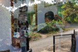 Siswandi memotong rambut pelanggannya di Kelurahan Banjarsari, Glagah, Banyuwangi, Jawa Timur, Selasa (12/6). Siswandi merupakan warga yang berprofesi sebagai tukang potong rambut yang menyambi sebagai relawan penjaga perlintasan kereta api di Banjarsari, yang volume pemotongan rambutnya meningkat dari 10 orang menjadi 25 orang per hari menjelang Lebaran 2018 dengan biaya potong Rp 10.000 per orang. Antara Jatim/Seno/zk/18.