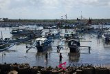 Anak nelayan berjalan di dekat perahu yang ditambatkan di Pantai Grajagan, Purwoharjo, Banyuwangi, Jawa Timur, Kamis (14/6). Ratusan perahu nelayan ditambatkan atau tidak melaut menjelang Hari Raya Idul Fitri 1439 H dan akan kembali melaut pada H+7 Lebaran. ANTARA FOTO/Seno/wdy/2018