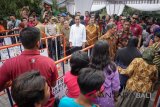 Presiden Joko Widodo menanti warga yang ingin menyalaminya saat pembagian sembako, di Solo, Jawa Tengah, Sabtu (16/6). Presiden memanfaatkan lebaran di Kota Solo dengan membagikan 4000 paket sembako kepada warga. ANTARA FOTO/Mohammad Ayudha/wdy/2018