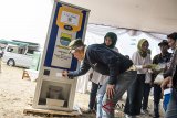 Warga mengantre pengambilan beras dengan mesin ATM beras seusai peluncuran di Lapangan Urugan, Bandung, Jawa Barat, Selasa (31/7). Pemerintah Kota Bandung akan menyebar enam unit ATM beras di enam kecamatan secara bertahap yang ditempatkan diberbagai rumah ibadah untuk mempermudah penyaluran beras kepada masyarakat kurang mampu. ANTARA JABAR/M Agung Rajasa/agr/18.
