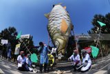 Aktivis lingkungan yang tergabung dalam Ecoton mengangkat poster di samping replika ikan yang telah tercemar limbah popok saat aksi di Surabaya, Jawa Timur, Selasa (31/7). Dalam aksinya mereka menyerukan agar Pemerintah menyikapi masalah limbah popok sekali pakai yang terbuang di Sungai Brantas karena menurut data mereka diperkirakan sedikitnya 1 juta sampah popok dibuang di sungai itu dan menyebabkan pencemaran lingkungan. Antara Jatim/Zabur Karuru/18