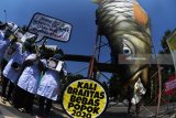 Aktivis lingkungan yang tergabung dalam Ecoton mengangkat poster di samping replika ikan yang telah tercemar limbah popok saat aksi di Surabaya, Jawa Timur, Selasa (31/7). Dalam aksinya mereka menyerukan agar Pemerintah menyikapi masalah limbah popok sekali pakai yang terbuang di Sungai Brantas karena menurut data mereka diperkirakan sedikitnya 1 juta sampah popok dibuang di sungai itu dan menyebabkan pencemaran lingkungan. Antara Jatim/Zabur Karuru/18