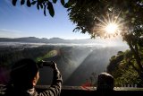 Warga memotret matahari terbit di Desa Ciburial Kabupaten Bandung, Jawa Barat, Sabtu (7/7). Badan Meteorologi, Klimatologi dan Geofisika (BMKG) mencatat, suhu minimum di Kota Bandung mencapai 16,4 derajat celcius akibat adanya aliran massa dingin di sebelah selatan garis khatulistiwa. ANTARA JABAR/Raisan Al Farisi/agr/18
