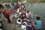 Sejumlah warga memanfaatkan sumbatan aliran Sungai Cileungsi untuk mencuci pakaian di kawasan Citeureup , Bogor, Jawa Barat, Sabtu (21/7). Musim kemarau berdampak pada sumur warga didaerah tersebut mengering sehingga warga memanfaatkan sungai untuk kegiatan mandi, cuci dan kakus . ANTARA JABAR/Yulius Satria Wijaya/agr/18.
