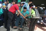 Petugas membantu jamaah calon haji (JCH) Kloter pertama dari Kabupaten Situbondo saat tiba di Asrama Haji Embarkasi Surabaya (AHES), Surabaya, Jawa Timur, Senin (16/7). Panitia Penyelenggara Ibadah Haji (PPIH) Embarkasi Surabaya menerima kedatangan 445 jamaah calon haji kelompok terbang (kloter) pertama dari Kabupaten Situbondo untuk dikaratina sebelum diberangkatkan ke Arab Saudi pada Selasa (17/7). Antara jatim/Moch Asim/18