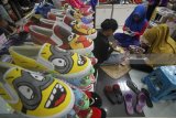 Pekerja menyelesaikan pembuatan sepatu lukis 