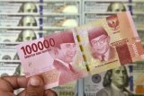 Petugas jasa penukaran valuta asing memeriksa lembaran mata uang rupiah dan dollar AS di Jakarta, Senin (2/7/2018). Mata uang rupiah di pasar spot exchange berada di level Rp14.375 per dolar AS atau terdepresiasi 50 poin atau 0,35 persen dibandingkan perdagangan sebelumnya yang berada pada nilai Rp14.325. (ANTARA/Puspa Perwitasari) 