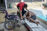 Pelatih dari atlet renang tunadaksa asal Kabupaten Bogor, Athar membantu untuk menaiki kursi roda seusai menjalani pertandingan renang gaya dada 50 meter dalam ajang Pekan Paralimpik Pelajar Daerah (Pepaperda) II di Kolam Renang Universitas Pendidikan Indonesia (UPI), Bandung, Jawa Barat, Rabu (25/7). Pepaperda ke II yang diikuti oleh 248 atlet penyandang disabilitas dari 25 Kota dan Kabupaten di Jawa Barat tersebut diadakan untuk mempersiapkan atlet untuk dapat berkompetisi dalam ajang Pekan Paralimpik Pelajar Tingkat Nasional. ANTARA JABAR/Raisan Al Farisi/agr/18