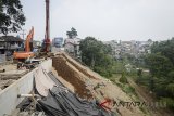 Pekerja dengan menggunakan alat berat melakukan proses perbaikan jalur yang longsor di Jalan Raya Bogor-Sukabumi, Cikereteg, Kabupaten Bogor, Jawa Barat, Sabtu (14/7). Pekerja mengatakan, longsor akibat intensitas hujan yang tinggi pada Februari lalu yang menyebabkan tiga ruko amblas tersebut akan rampung pada akhir Agustus mendatang. ANTARA JABAR/Raisan Al Farisi/agr/18