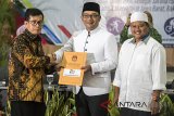 Ketua KPU Jabar Yayat Hidayat (kiri) memberikan berkas berita acara dan surat keputusan kepada pasangan Gubernur dan Wakil Gubernur Jawa Barat terpilih Ridwan Kamil (tengah) dan Uu Ruzhanul Ulum (kanan) saat rapat pleno terbuka Penetapan pasangan calon terpilih pada Pilgub Jabar 2018 di Bandung, Jawa Barat, Selasa (24/7). KPU Jawa Barat menetapkan Ridwan Kamil dan Uu Ruzhanul Ulum sebagai Gubernur dan Wakil Gubernur terpilih Pilgub Jabar 2018 dengan perolehan suara 7.226.254 suara atau 32,88 persen. ANTARA JABAR/M Agung Rajasa/agr/18.
