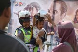 Polisi wanita menggendong anak saat melakukan promosi film 22 Menit pada kegiatan Car Free Day di Kota Kediri, Jawa Timur, Minggu (15/7). Film 22 Menit yang meberikan pesan untuk meningkatkan kewaspadaan dan kebersamaan dalam menghadapi terorisme itu akan tayang serentak pada 19 Juli mendatang di seluruh jaringan bioskop XXI. Antara Jatim/Prasetia Fauzani/mas/18.