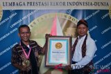 Ketua Umum Lembaga Prestasi Indonesia-Dunia (LEPRID) Paulus Pangka (kanan) menyerahkan piagam LEPRID kepada Ibrahim Bire Logo (kiri) atas prestasinya sebagai pemrakarsa pembuatan kain tenun ikat tradisional Sabu Raijua terpanjang dengan motif bertemakan NKRI, di Semarang, Jawa Tengah, Minggu (15/7/2018). Pembuatan kain tenun ikat sepanjang 68 meter dengan lebar 91 cm tersebut menghabiskan anggaran sebesar Rp90 juta dan tercatat sebagai rekor prestasi ke-356 LEPRID. (ANTARA FOTO/R. Rekotomo)