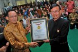 Presiden Direktur PT. Charoen Pokphand Indonesia yang juga Ketua Umum Charoen Pokphand Foundation, Thomas Effendy (kiri) menerima piagam penghargaan dari Senior Manager Museum Rekor Dunia Indonesia (MURI), Yusuf Ngadri (kanan) saat acara syukuran di Ponpes Tebuireng, Jombang, Jawa Timur, Rabu (11/7/2018). Charoen Pokphand Foundation berhasil mencatat rekor Museum Rekor Dunia Indonesia (MURI) kategori pelatihan penguatan pendidikan karakter secara bersambung kepada guru terbanyak, yakni 1092 orang guru di 14 daerah periode 13 September 2017 - 11 Juli 2018. (ANTARA FOTO/Syaiful Arif)