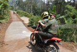 Komandan Pusat Teritorial Mabes TNI Angkatan Darat (Danpusterad Mabesad) Mayjen TNI Hartomo (kanan) dibonceng sepeda motor oleh personel TNI saat meninjau kegiatan TNI Manunggal Membangun Desa (TMMD) di Desa Bodag, Kecamatan Kare, Kabupaten Madiun, Jawa Timur, Kamis (19/7). Mayjen TNI Hartomo meninjau sejumlah kegiatan TMMD, antara lain pembangunan Rumah Tidak Layak Huni (RTLH), pembuatan jalan rabat beton menuju objek wisata Selo Gedong di lereng Gunung Wilis, pengobatan gratis dan wawasan kebangsaan. Antara Jatim/Siswowidodo/mas/18.