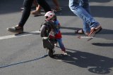 Seekor monyet mengenakan topeng dan membawa sepeda motor mainan saat Car Free Day (CFD) di jalan Doho, Kota Kediri, Jawa Timur, Minggu (15/7). Pertunjukan Topeng Monyet masih dapat dijumpai meskipun telah dilarang oleh Direktorat Jenderal Konservasi Sumber Daya Alam dan Ekosistem Balai Besar Konservasi Sumber Daya Alam (BKSDA) Jawa Timur sejak 18 Mei 2018. Antara Jatim/Prasetia Fauzani/mas/18.