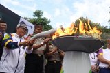 Bupati Banyuwangi Abdullah Azwar Anas (kiri), menyalakan kaldron saat menyambut Torch Relay Asian Games 2018 berkeliling kota di Banyuwangi, Jawa Timur, Minggu (22/7). Masyarakat Banyuwangi menyambut kirab obor (Torch Relay) Asian Games 2018 dengan tarian gandrung oleh ratusan penari dan aneka atraksi. Antara Jatim/Seno/18.