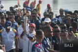 Menteri Koordinator bidang Pembangunan Manusia dan Kebudayaan Puan Maharani membawa obor Asian Games 2018 setelah dibawa berselancar ke tengah laut di Pantai Kuta, Bali, Senin (23/7). Torch Relay Asian Games 2018 melintasi empat kabupaten di Bali dengan arak-arakan berkeliling di sejumlah obyek wisata. Antaranews Bali/Nyoman Budhiana/2018.