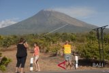 Wisatawan berfoto dengan latar belakang Gunung Agung di Desa Batuniti, Karangasem, Bali, Rabu (4/7). Pusat Vulkanologi dan Mitigasi Bencana Geologi (PVMBG) masih menetapkan Gunung Agung pada level siaga dan erupsi strombolian masih berpotensi terjadi kembali. ANTARA FOTO/Nyoman Budhiana/wdy/2018