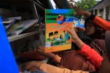 Sejumlah siswa meminjam buku dari mobil perpustakaan keliling di SDN 9-15-18 Desa Ujong Baroh, Johan Pahlawan, Aceh Barat, Aceh, Jumat (20/7). Mobil perpustakaan keliling milik Dinas Perpustakaan dan Arsip Kabupaten Aceh Barat setiap hari mengunjungi sekolah-sekolah sebagai upaya meningkatkan minat baca di kalangan pelajar sekaligus mengatasi keterbatasan perpustakaan di sekolah serta untuk memperkuat program gerakan Ayo Membaca. ANTARA FOTO/Syifa Yulinnas/foc/18.