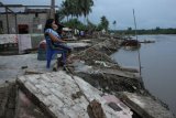 Warga berdiri diantara sisa puing-puing rumah yang tidak terseret arus air Sungai Konaweha saat terjadi banjir di Desa Muara Sampara, Kecamatan Kapoiala, Konawe, Sulawesi Tenggara, Kamis (12/7). 28 unit rumah warga di dua desa yaitu Desa Lalibue dan Desa Muara Sampara hilang terseret banjir dari luapan air Sungai Konaweha pada Rabu (11/7) sore. Warga mengaku selain faktor intensitas hujan tinggi selama dua pekan, luapan air sungai juga disebabkan tidak adanya serapan air hujan akibat aktivitas penambangan nikel dari pabrik simelter. ANTARA FOTO/Jojon/pd/18.