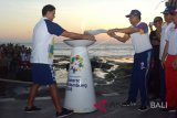 Aktor Hamish Daud (kiri) menyerahkan obor kepada Sekda Kabupaten Tabanan, Nyoman Wirna Ariwangsa (keempat kanan) saat menyambut Torch Relay Asian Games 2018 di objek wisata Tanah Lot, Kabupaten Tabanan, Bali, Senin (23/7). Masyarakat Kabupaten Tabanan menyambut kirab obor (Torch Relay) Asian Games 2018 dengan kesenian Okokan dan aneka atraksi serta dilanjutkan bermalam di Istana Negara Tampaksiring, Bali. ANTARA FOTO/Wira Suryantala/wdy/2018.