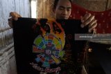 Pekerja memperlihatkan batik motif Asian Games di industri rumahan 