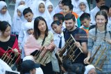 Sejumlah pelajar sekolah dasar bersama sejumlah mahasiswa asing bermain angklung bersama di Surabaya, Jawa Timur, Selasa (31/7). Kegiatan itu bertujuan untuk mengenalkan alat musik tradisional Indonesia kepada mahasiswa asing itu. Antara Jatim/Didik Suhartono/18