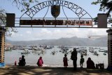 Pengunjung berada di pinggir pantai dengan latar belakang perahu nelayan di Pantai Popoh Tulungagung, Jawa Timur, Minggu (12/8). Dua hari teakhir nelayan setempat mengaku terpaksa tidak melaut karena gelombang tinggi. Antara Jatim/Prasetia Fauzani/mas/18.