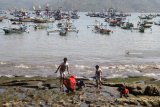 Pengunjung mecari kerang di pinggir pantai dengan latar belakang perahu nelayan di Pantai Popoh Tulungagung, Jawa Timur, Minggu (12/8). Dua hari teakhir nelayan setempat mengaku terpaksa tidak melaut karena gelombang tinggi. Antara Jatim/Prasetia Fauzani/mas/18.