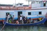 Sejumlah penumpang turun dari perahu layar motor ke perahu penghubung di Pelabuhan Kalbut, Mangaran, Situbondo, Jawa Timur, Kamis (16/8). Puluhan penumpang dari Pulau Poday, Madura terpaksa menaiki perahu layar motor dengan hewan ternak karena belum adanya kapal atau perahu penumpang. Antara Jatim/Seno/mas/18.