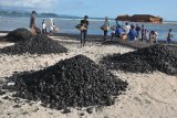 Warga bersama nelayan membersihkan tumpahan batu bara dari kapal tongkang yang kandas di perairan pantai Ujung Kareng, Lhoknga, Aceh Besar, Aceh, Jumat (3/8). Plt Gubernur Aceh Nova Iriansyah meminta perusahaan kapal tongkang yang mengangkut sebanyak 7.000 ton batu bara untuk kebutuhan PT Lafarge Semen Indonesia di daerah itu untuk membersihkan tumpahan batu bara dan memulihkan ekosistem pantai yang rusak. (ANTARA FOTO/Ampelsa/aww/18)