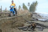 Warga melintasi badan jalan yang terkena abrasi di Desa Suak Puntong, Kuala Pesisir, Nagan Raya, Aceh, Selasa (31/7). Dampak gelombang tinggi yang terjadi sejak dua pekan terakhir mengakibatkan jalan lintas di kawasan objek wisata pantai sepanjang dua kilometer putus total. (ANTARA FOTO/Syifa Yulinnas/wsj/18)