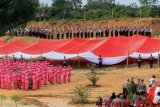 Personel Kepolisian Polres Aceh Utara melakukan penghormatan kepada Bendera Merah Putih raksasa di Bukit Sentang, Lhoksukon, Aceh Utara, Aceh, Rabu (8/8). Bendera raksasa dengan panjang 60 meter, lebar 50 meter dan berat 300kg tersebut dikibarkan di perbukitan kawasan bekas konflik Aceh, dalam rangka menyambut HUT ke-73 Kemerdekaan RI sekaligus semangat Polri menyukseskan Asian Games 2018. (ANTARA FOTO/Rahmad/ama/18)