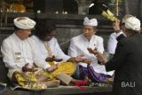 Pemuka agama Hindu memercikkan air suci kepada Wakil Presiden dan Sekretaris Grup Bank Dunia Yvonne Tsikata (kedua kiri) disaksikan Gubernur Bali Made Mangku Pastika (kedua kanan) dan Wakil Bupati Karangasem I Wayan Artha Dipa (kiri) saat melaksanakan Ritual 'Matur Piuning' di Pura Besakih, Karangasem, Bali, Kamis (2/8). Ritual dan doa bersama tersebut dilakukan dengan tujuan memohon kelancaran selama pelaksanaan pertemuan tahunan IMF-World Bank 2018. ANTARA FOTO/Fikri Yusuf/wdy/2018.