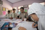 Anggota polisi mengajar di salah satu sekolah dasar negeri (SDN) di Blitar, Jawa Timur, Rabu (26/9). Polres Blitar menerjunkan personel untuk membantu proses belajar mengajar disejumlah SD hingga SMA yang sampat lumpuh sejak Senin (24/9) salu akibat aksi mogok sejumlah Guru Tidak Tetap (GTT) yang memprotes program rekrutmen CPNS 2018. Antara Jatim/Irfan Anshori/mas/18.