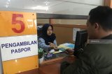 Petugas memberikan paspor kepada pemohon di Kantor Imigrasi Kelas II Blitar, Jawa Timur, Kamis (27/9). Guna meningkatkan kualitas pelayanan, Imigrasi Blitar sedang mengujicoba sistem pemberitahuan berbasis pesan pendek bernama Passport Reminder. Antara Jatim/Irfan Anshori/mas/18.