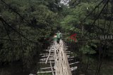 Warga melintasi jembatan gantung bambu yang rusak di Pondok Rajeg, Bogor, Jawa Barat, Selasa (25/9). Jembatan gantung penghubung desa Panjang Pondok Rajeg dan desa Utan Citayam tersebut sudah rusak dan lapuk sehingga dapat membahayakan warga yang melintas. ANTARA JABAR/Yulius Satria Wijaya/agr/18.