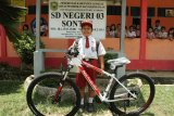 Siswa SD Nursaka (8 tahun) berfoto bersama sepeda barunya di SDN 03 Sontang, Kecamatan Entikong, Kabupaten Sanggau, Kalbar, Kamis (13/8). Nursaka yang setiap hari melintasi dua negara dari Malaysia ke Indonesia melalui PLBN Entikong untuk bersekolah tersebut, mendapat hadiah sepeda dan peralatan sekolah dari Presiden Joko Widodo. ANTARA FOTO/HS Putra/jhw/18