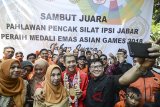 Peraih medali emas cabang olahraga silat dalam perhelatan Asian Games 2018 Hanifan Yudani Kusuma (tengah) menunjukkan medalinya saat pawai penyambutan di Bandung, Jawa Barat, Senin (3/9). Penyambutan yang diinisiasi oleh Ikatan Pencak Silat Indonesia (IPSI) Jabar tersebut dilakukan dalam rangka merayakan prestasi yang diraih oleh atlet silat Jabar yang meraih empat dari 14 medali emas dalam cabang olahraga silat. ANTARA JABAR/Raisan Al Farisi/agr/18.