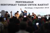 Presiden Joko Widodo (tengah) melambaikan tangan kepada warga saat penyerahan sertifikat tanah untuk rakyat di Surabaya, Kamis (6/9). Pemerintah menargetkan menyerahkan sertifikat tanah sebanyak 7 juta sertifikat tanah untuk rakyat selama 2018. Antara Jatim/Zabur Karuru/18
